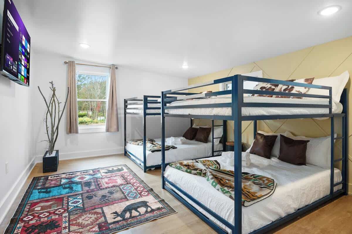 Una habitación con literas, un televisor de pantalla plana, una ventana con cortinas y una alfombra estampada.