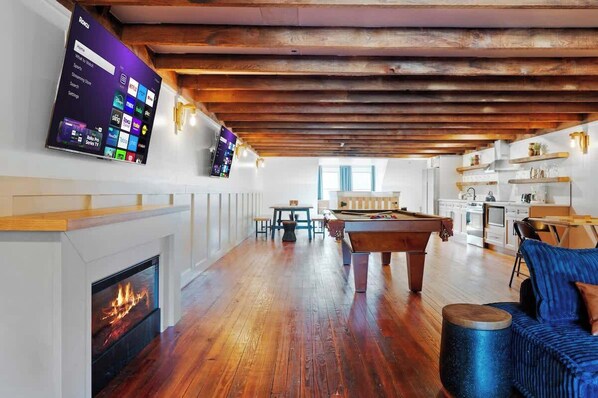 Amplia sala de estar con mesa de billar, chimenea y televisor con pantalla de inicio.