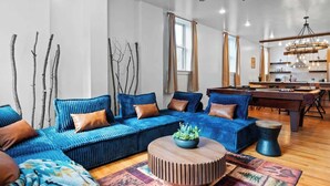 A modern living room with a sectional sofa, a round coffee table, and a dining area with a wooden table and chairs. - The Grand Pocono Getaway Waterparks & Raceway! (Pocono Summit)