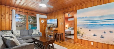 A cozy cabin interior with a living room, a dining area, and a bedroom.