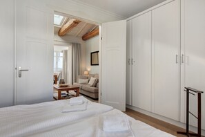 Een hotelkamer met een groot bed, een kledingkast, een bureau en een raam met gordijnen.
