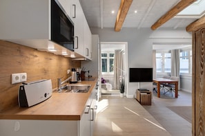 Een moderne keuken met een houten aanrechtblad, roestvrijstalen apparatuur en een ingebouwde magnetron.