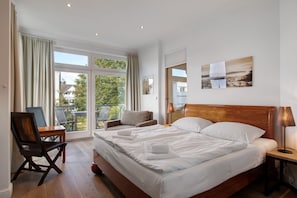 Een hotelkamer met een groot bed, een bureau, een stoel en een balkon met uitzicht.