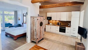 A modern interior with a bed, kitchenette, and a dining area. - Apartment "Halbinsel Mönchgut" with Balcony and Wi-Fi (Binz)