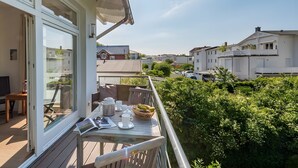 A balcony with a table set for breakfast, a window overlooking a residential area, and a clear sky. - Apartment "Halbinsel Mönchgut" with Balcony and Wi-Fi (Binz)