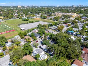 An aerial view of a residential area with houses, a sports field, and a parking lot. - Tropical Haven | Cozy 1 BR Caribbean Getaway (Miami)