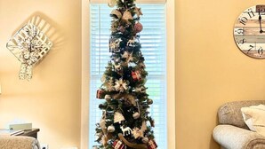 Un salon avec un sapin de Noël, une horloge et une cheminée.