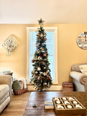 Ein Wohnzimmer mit Weihnachtsbaum, einer Uhr und einem Kamin.