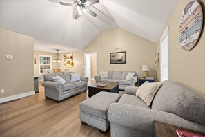 Un salon spacieux avec un plafond haut, un ventilateur de plafond et une grande horloge au mur.