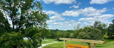 A sign for Lake Cumberland Stays & Events in a grassy area with a clear sky.