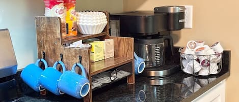 A kitchen with a coffee maker, a kettle, and a coffee bean storage unit.