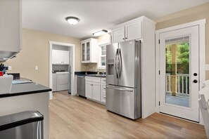 Une cuisine moderne dotée d’appareils électroménagers en acier inoxydable, de meubles blancs et d’un plancher en bois.