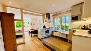 Une cuisine moderne avec un coin repas, un plancher en bois et de grandes fenêtres.