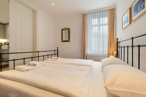 Habitación de hotel con dos camas, un espejo, una ventana con cortinas y un radiador.