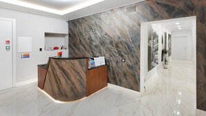 Ein Empfangsbereich mit Holzausstattung, einer Wand im Marmor-Design und einem sauberen, gefliesten Boden.