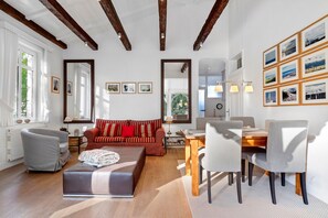 A modern living room with a sofa, ottoman, and dining area with chairs and a table. - Apartment 'Die Stubnitz' with Winter Garden and Balcony Effect (Binz)