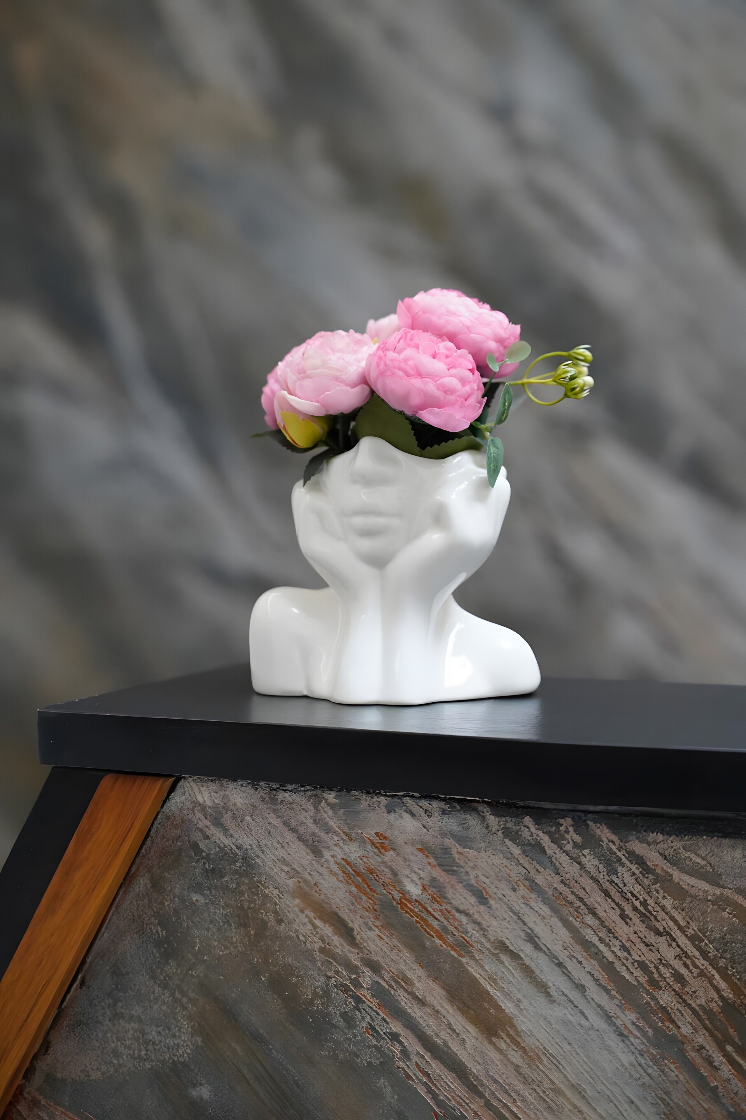 A white ceramic vase with a floral design on a black surface.