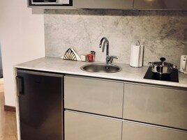Una cocina compacta con un lavamanos de acero inoxidable, lavavajillas integrado y una pequeña encimera.
