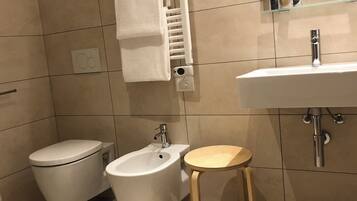 A modern bathroom with a toilet, bidet, and sink.