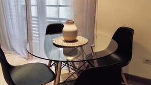 A glass table with a woven placemat, surrounded by black chairs, in a room with a window and curtains. - Palazzina B  (Genoa)