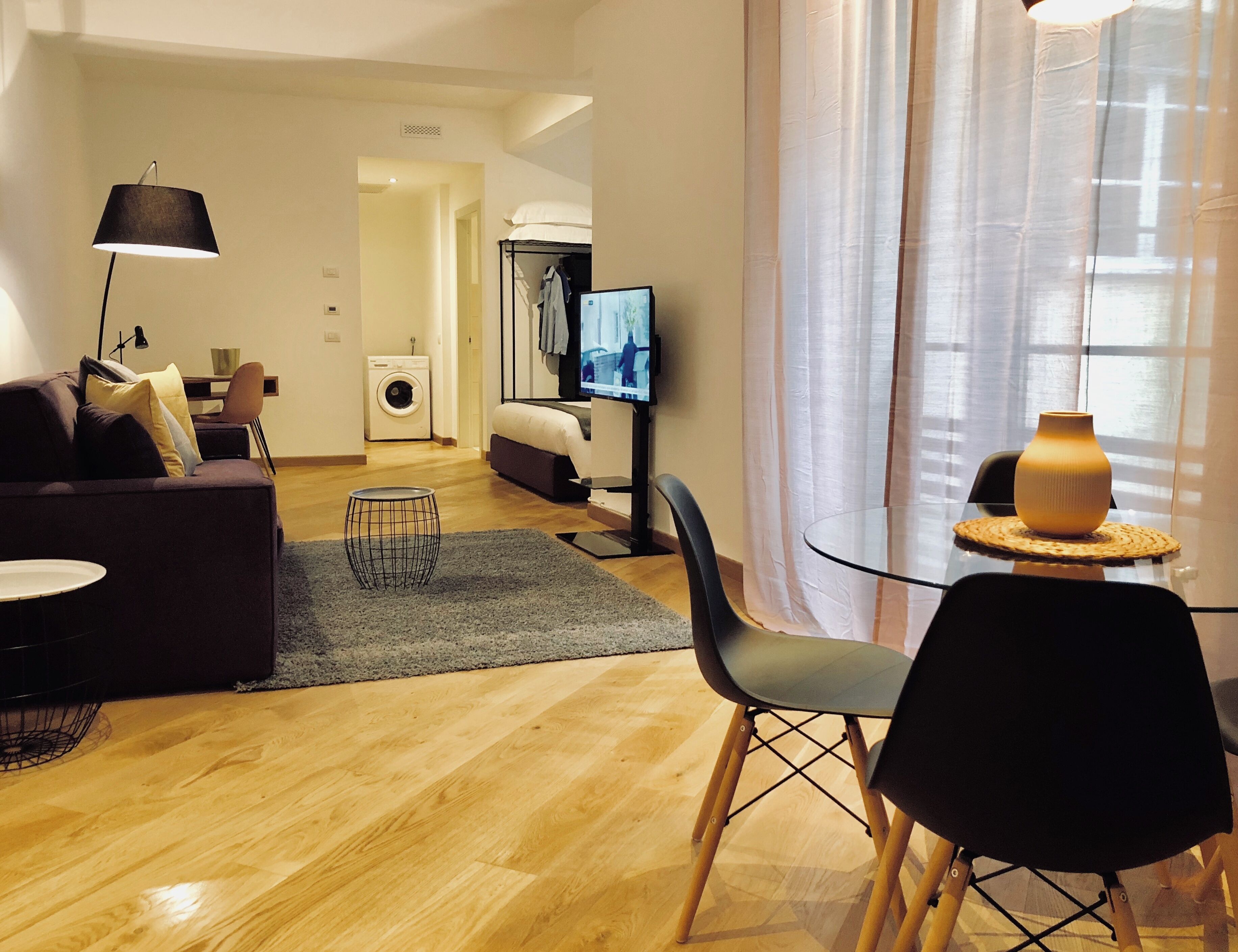 Una sala de estar moderna con un sofá, una mesa de centro, un televisor y un comedor con una silla y mesa.