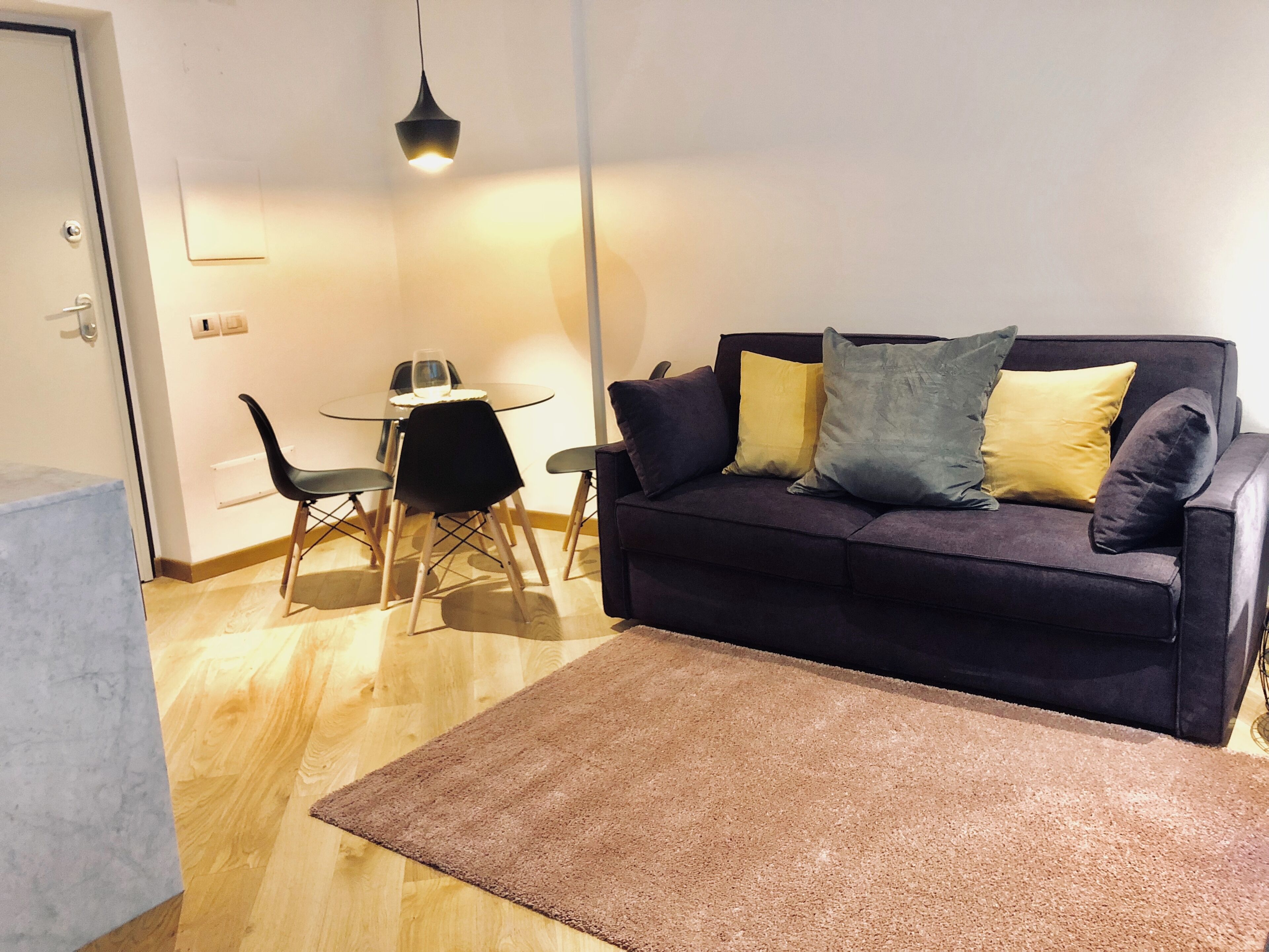 Un salon avec un canapé de couleur foncée, une table en verre et des chaises.