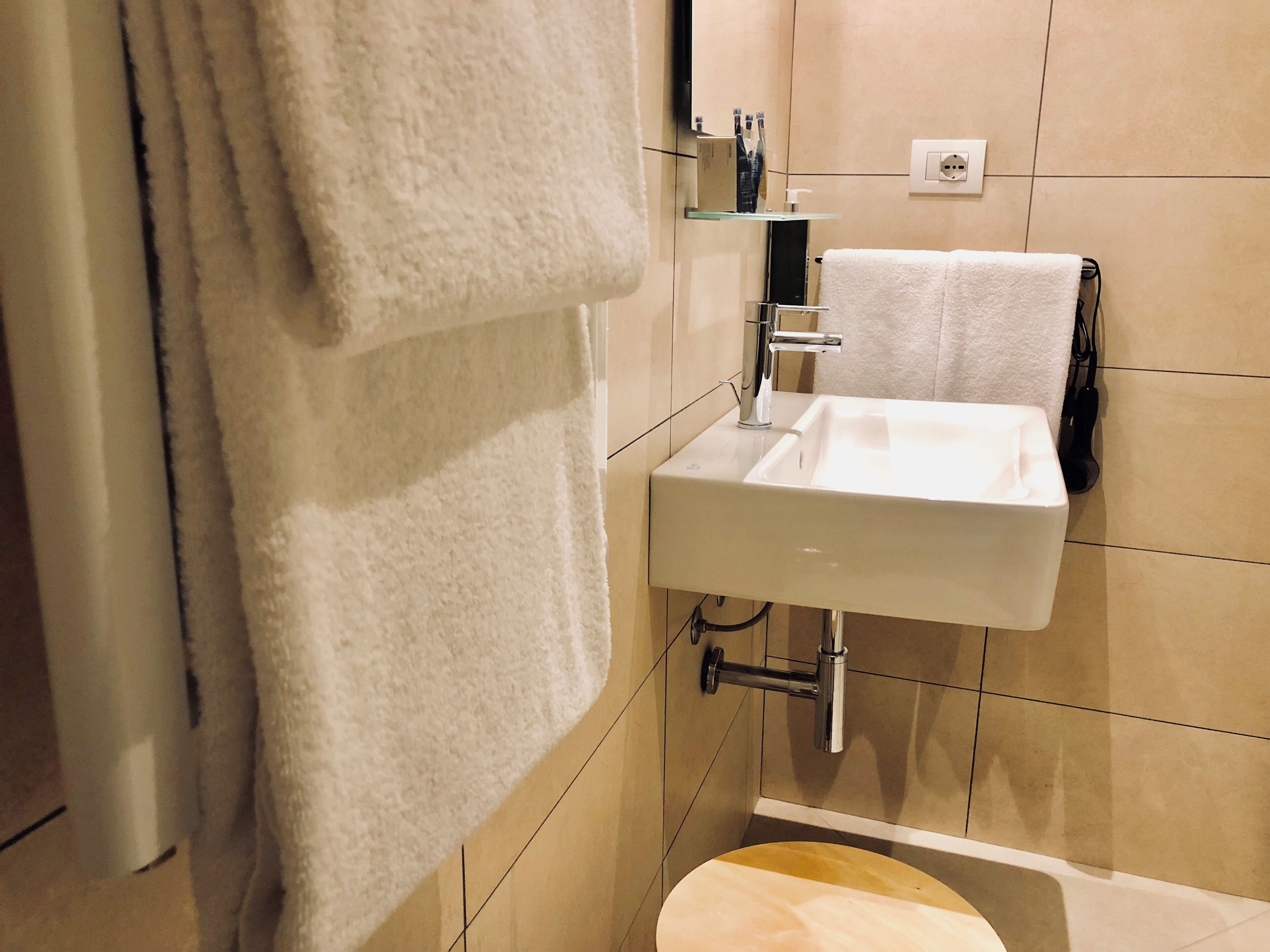 Ein Badezimmer mit einem weißen Waschbecken, einem Handtuch an der Wand und einer Toilette.