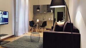 A modern living room with a dark sofa, a coffee table, and a TV on the wall. - Palazzina B  (Genoa)