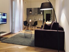 Una sala de estar moderna con un sofá oscuro, una mesa de centro y un televisor en la pared.