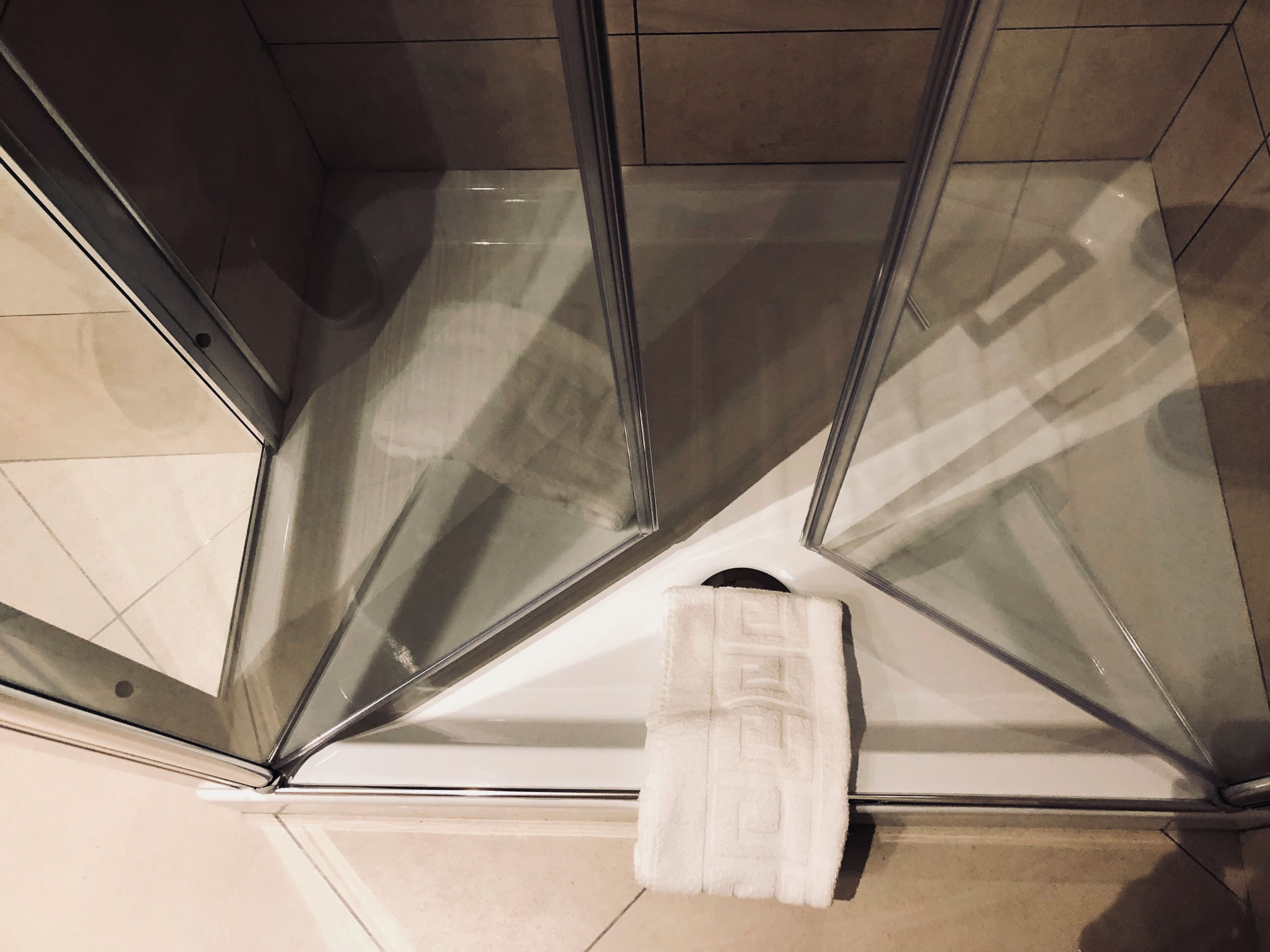 A corner of a room with a glass shower enclosure and a white towel hanging on the wall.