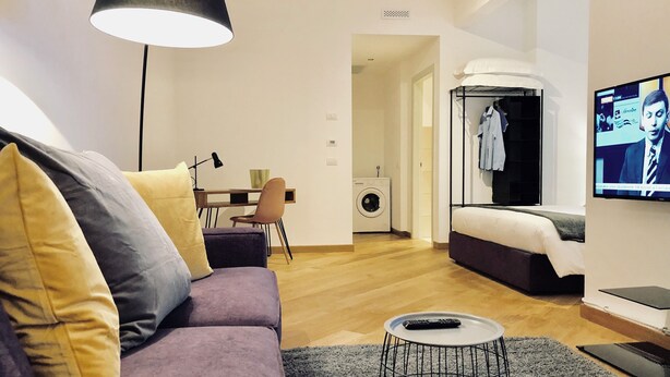 A modern living room with a purple sofa, a round coffee table, and a TV mounted on the wall. - Palazzina B  (Genoa)