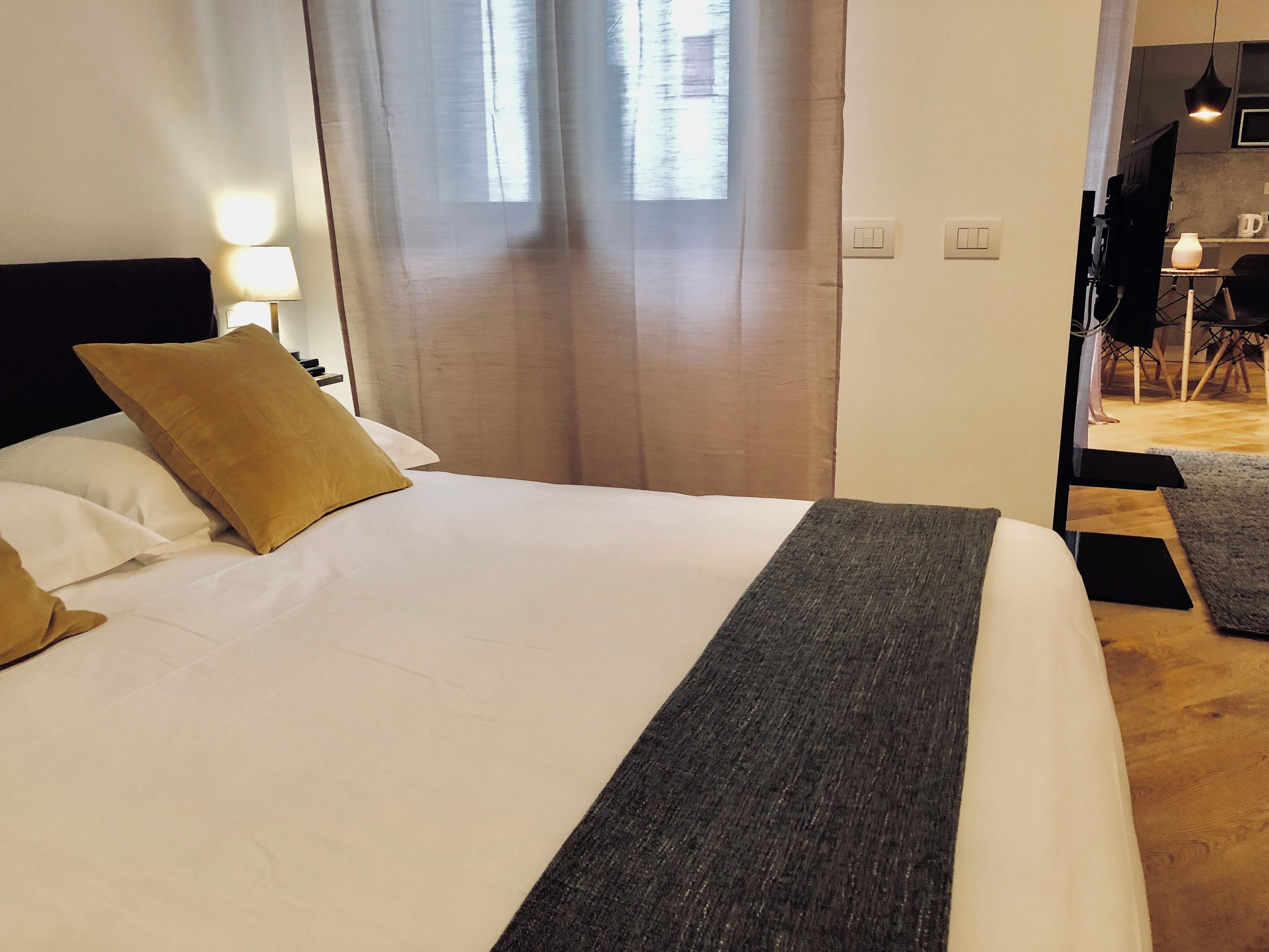A bed with white and brown pillows, a grey blanket, and a wooden headboard.