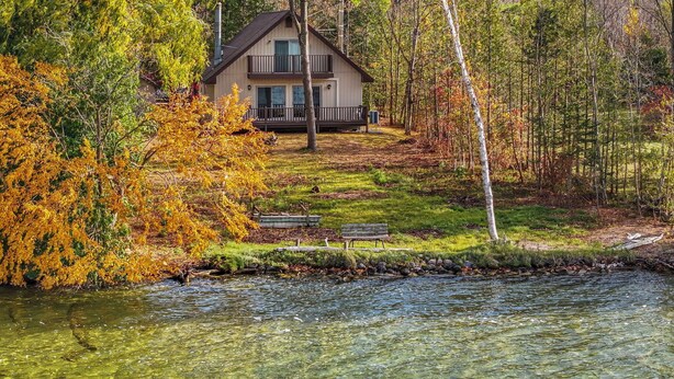 A cabin with a deck and a view of a river.