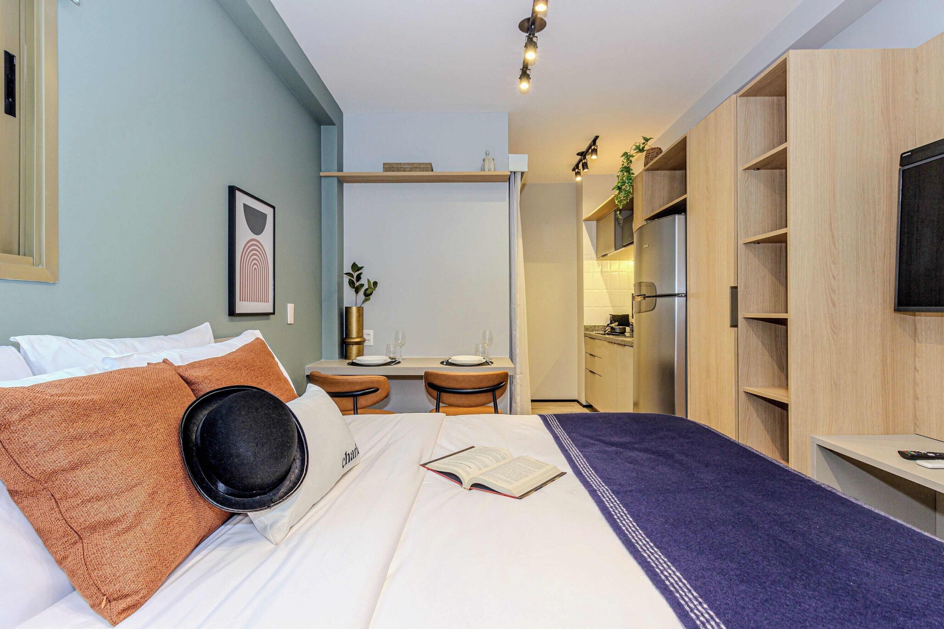 Ett hotellrum med en säng, ett skrivbord och ett litet kök.