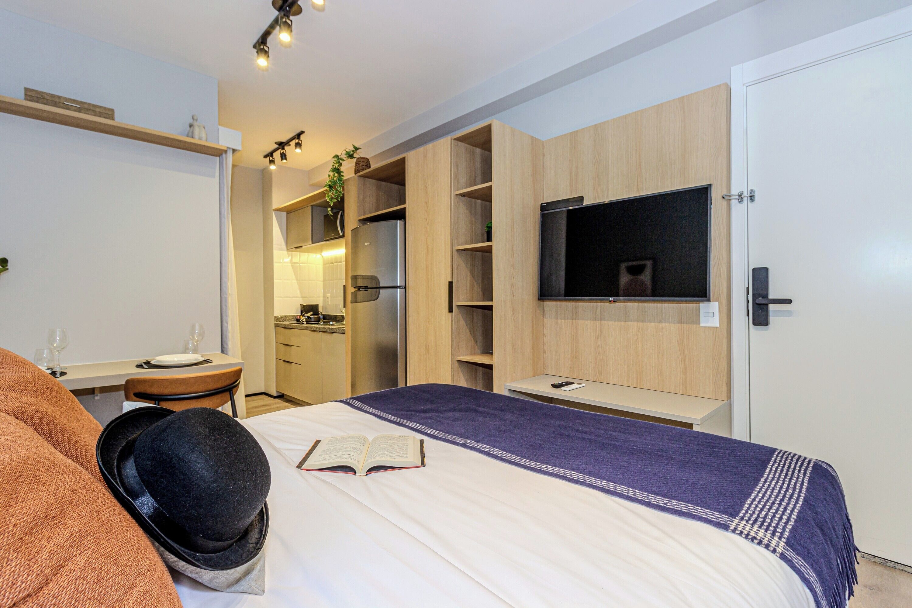 Une chambre d’hôtel moderne équipée d’un lit, d’un bureau, d’un téléviseur fixé au mur et d’une armoire.