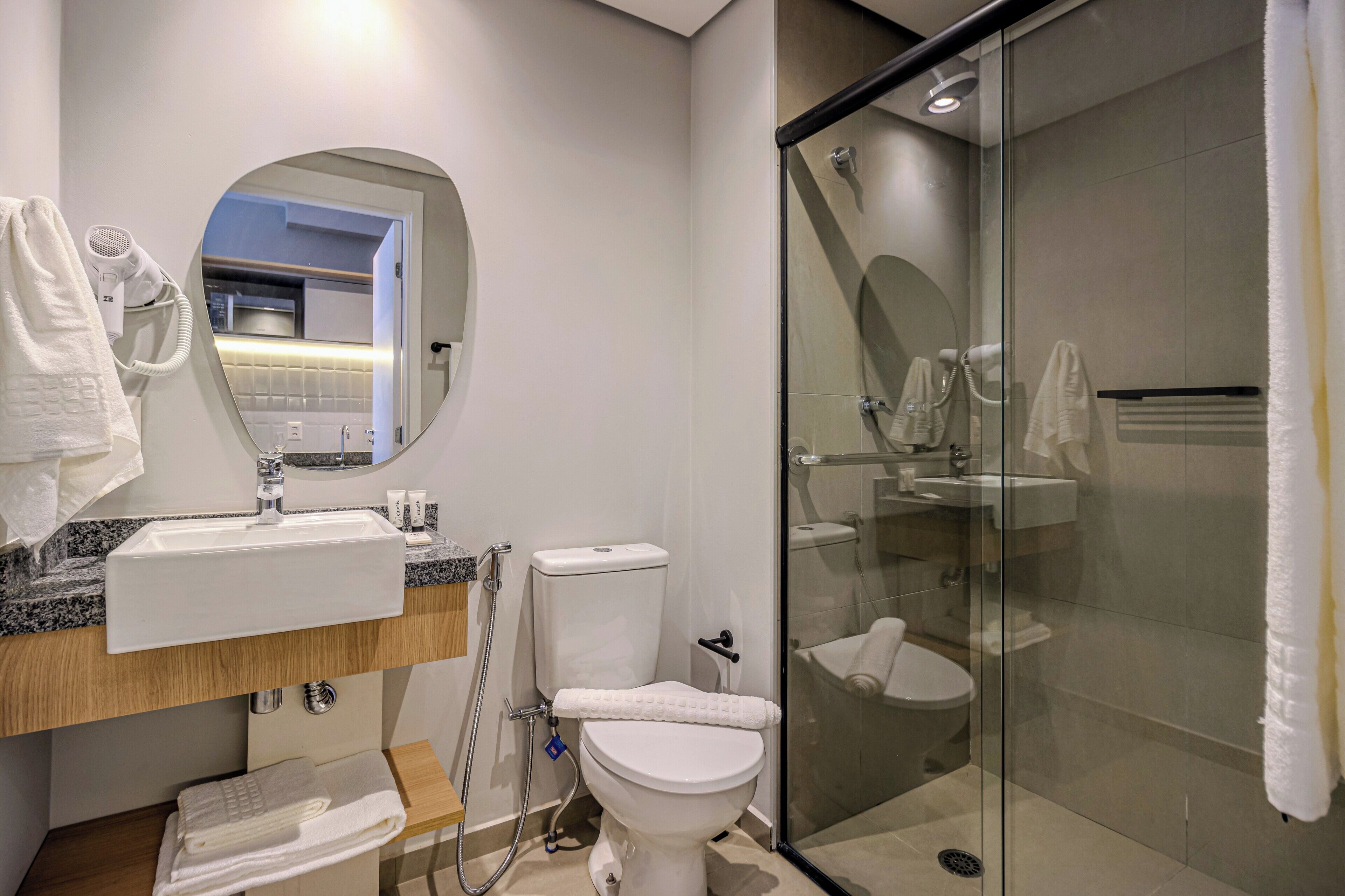 Un baño moderno con cabina de ducha de vidrio, lavabo con toallero y retrete.
