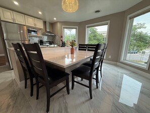 A modern kitchen with a large island, dark wooden chairs, and a marble floor. - *Riverview*Walk to Falls*2BDRM*Renovated*1st floor (Niagara Falls)
