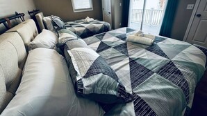 A hotel room with two beds, a window with blinds, a door, and a view of the outside.
