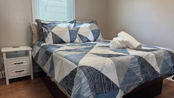 Een slaapkamer met een bed, nachtkastje en een raam met jaloezieën.