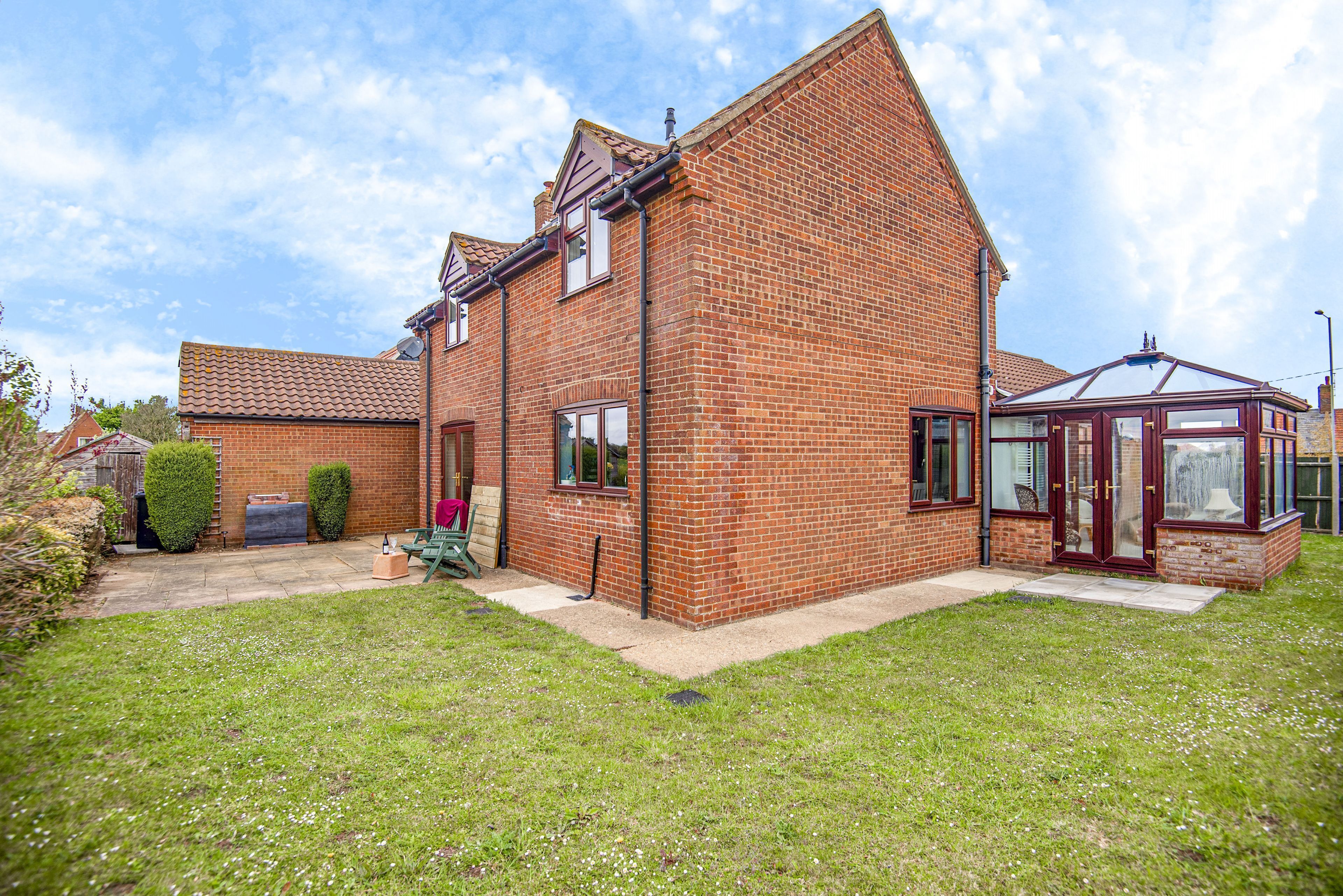 A two-story brick house with a conservatory, a garden, and a visible garage.