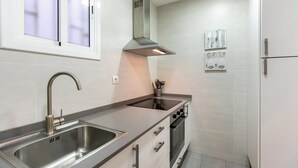 Eine moderne Küche mit Spüle aus Edelstahl, Dunstabzugshaube und Einbauofen.