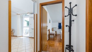 Um corredor com porta de madeira, um cabideiro e uma sala de jantar com mesa e cadeiras.