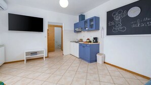 Une cuisine compacte avec des meubles bleus, un plan de travail blanc et un tableau noir orné de dessins.