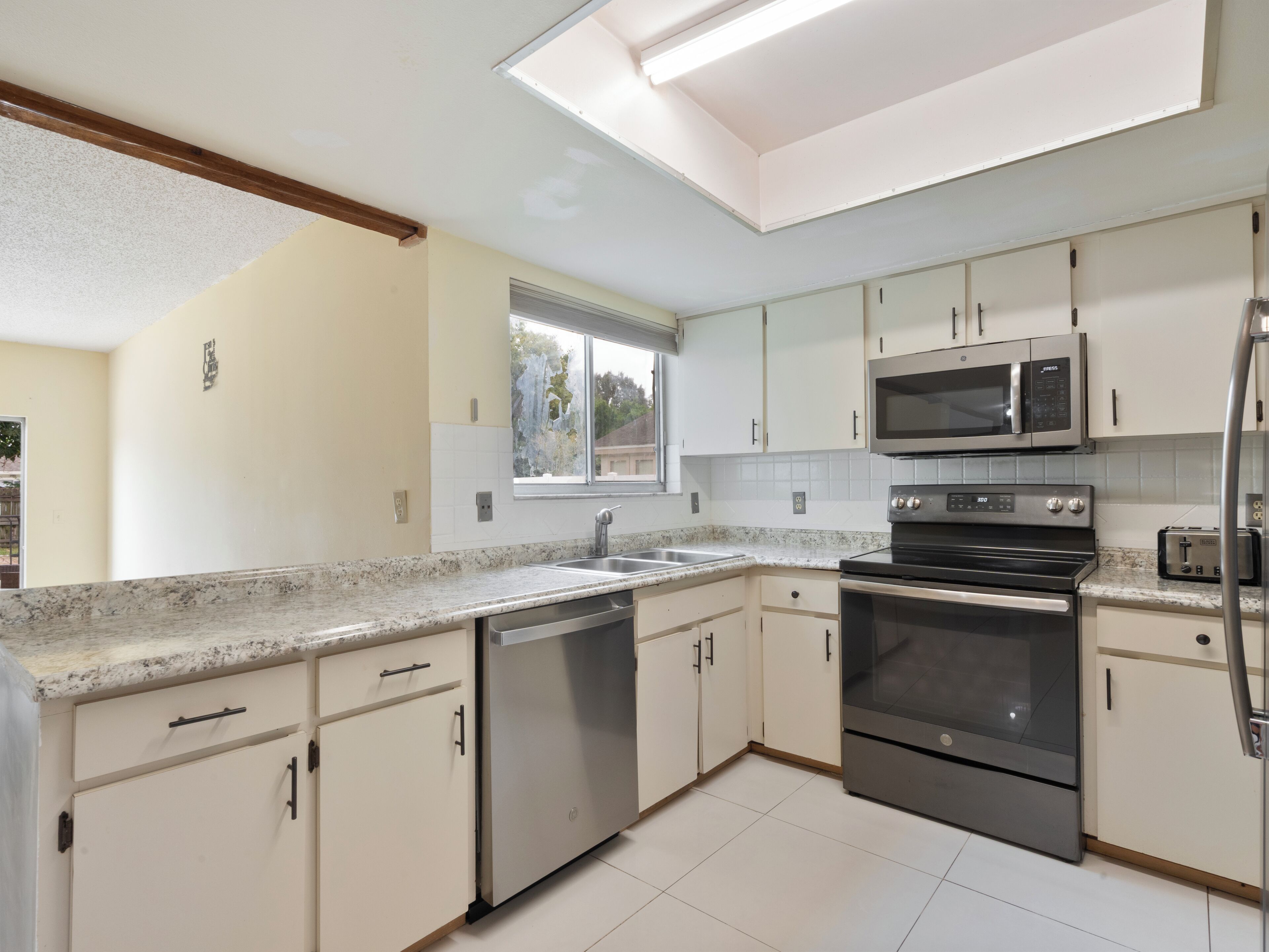 Una cocina moderna con gabinetes blancos, electrodomésticos de acero inoxidable y encimera de granito.