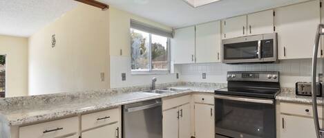 Una cocina moderna con gabinetes blancos, electrodomésticos de acero inoxidable y encimera de granito.