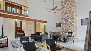 A spacious living area with a high ceiling, a stone accent wall, a fireplace, and a dining table with chairs. - Pleasant and RUSTIC 4-bedroom house in the heart of Orlando (Orlando)