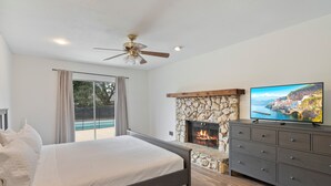 A bedroom with a bed, a stone fireplace, a television, and a ceiling fan. - Pleasant and RUSTIC 4-bedroom house in the heart of Orlando (Orlando)