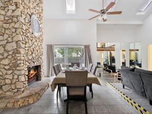 Un comedor con pared de piedra, chimenea y vista al exterior.