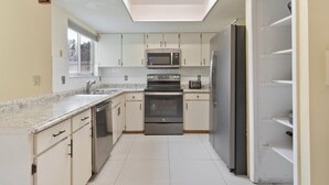 A modern kitchen with white cabinets, stainless steel appliances, a skylight, and a window. - Pleasant and RUSTIC 4-bedroom house in the heart of Orlando (Orlando)