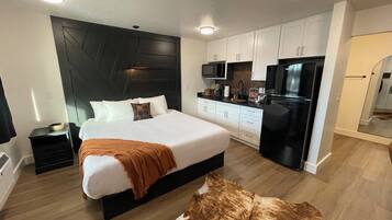 Un dormitorio moderno con una cama grande, un cabecero negro y suelo de madera.